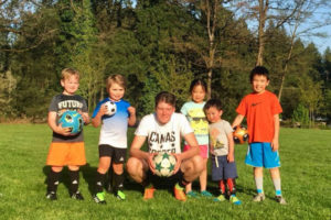 Brison Manandic (center), a senior at Camas High, poses with a few of the youngsters he's helped through his senior project, Cleats for Kids, which give new and gently used soccer cleats to young soccer player hopefuls. (Contributed photo courtesy of the Manandic family)