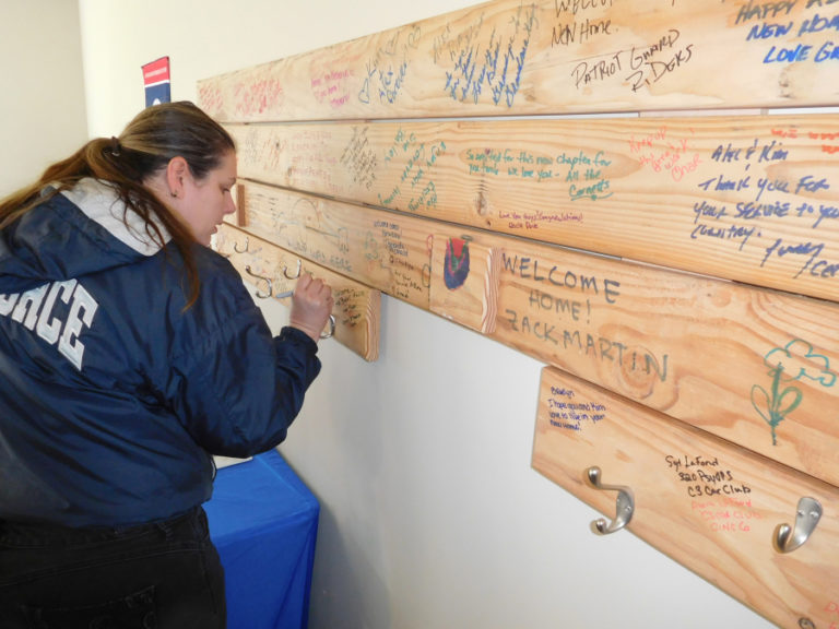 Naomi Raia, of Washougal, signs a greeting on a board in Alex and Kim Hussey&#039;s new garage on May 12. Some of the boards were signed during a community kickoff event hosted by Homes for our Troops at Washougal High School in 2017.