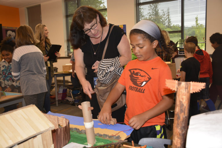 Washougal School Board member Donna Sinclair chats with Columbia River Gorge Elementary student Payton Williams about the plank house she created to represent the culture and lifestyle of the Northwest Coast Native Americans.