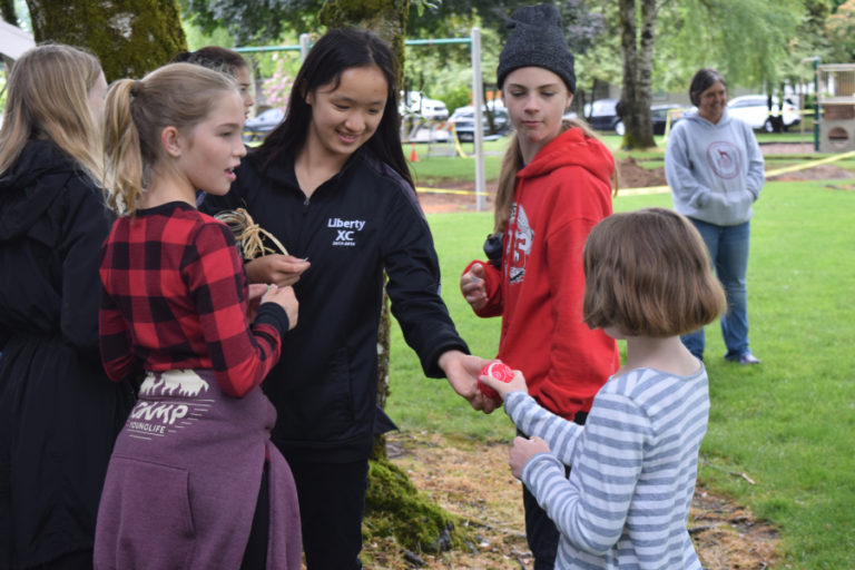 Odyssey Middle School seventh grader Grace Duffey hands a raffle winner a tennis ball prize during a fundraiser at Camas&#039; Goot Park.