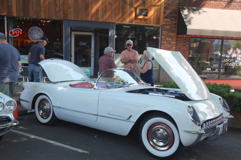 Steve Chaney (third from right) leans against his restored 1954 Chevy Corvette at the 2017 Camas Car Show. The pristine convertible, restored using all original parts, took home the Best in Show prize at last year&#039;s car show.
