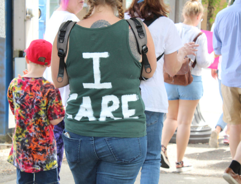 A woman wears an &quot;I Care&quot; shirt at the June 30 Families Belong Together march in Vancouver in response to a jacket stating, &quot;I really don&#039;t care.
