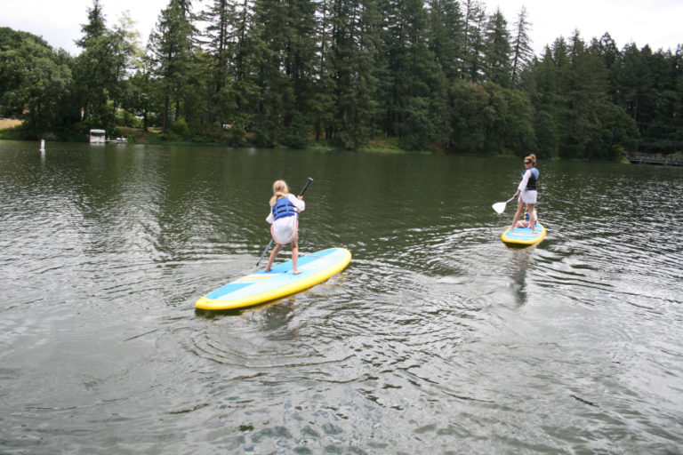 Evelyn Grabenkort (left) shows how she handles the big board with ease as she follows her mom, Amy Grabenkort, and younger sister, Lily, on Lacamas Lake.