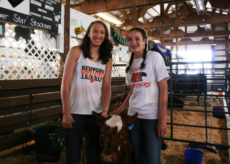 Washougal hoopers and sisters Beyonce Bea (left) and Skylar Bea (right) show off a family cow at the Skamania County Fair on Aug. 14.