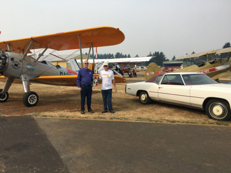 Camas-Washougal Aviation Association President Kent Mehrer (right) stands with an Apiary-Key King Security representative at the 2017 Wheels & Wings show, next to one of Mehrer's vintage 1940s Stearman planes.