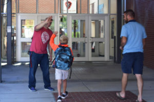 David Volke, a Liberty Middle School language arts and social studies teacher, greets students as they walk toward the front entrance on the first day of school, Tuesday, Sept. 4. 