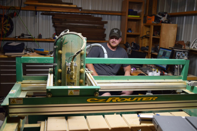 Wayne Christensen sits with the family&#039;s new routing machine, which he operates through a computer.