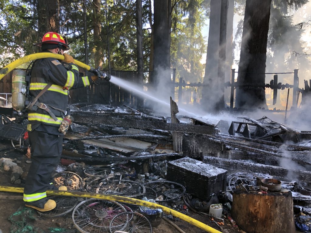 A Camas-Washougal Fire Department firefighter puts out a fire at an outbuilding in Washougal on Friday, Sept. 14. (Photo courtesy of the Camas-Washougal Fire Department)
