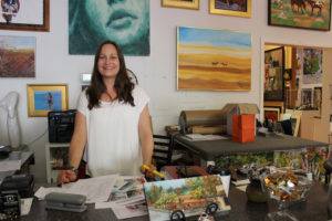 Maria Gonser stands behind her desk at the Attic Gallery. An upcoming addition will nearly double the size of the downtown Camas space. 