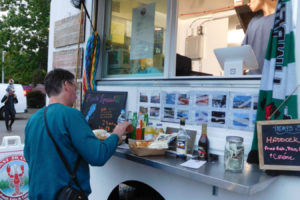 A customer adds sauce to his seafood order at the Coast to Coast Fresh Eats & Catering truck Sept. 15, as the owner's son, Zach Herndon, prepares for the next customer, during "Pirates in the Plaza," in downtown Washougal. Herndon's father, Jess Herndon (not pictured), started his food truck business in July 2018, and is normally located in the Camas Produce parking lot.