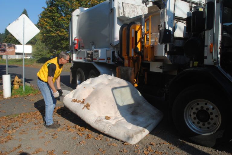 Garry Reed, Camas sanitation lead, drags a mattress into his truck&#039;s claw on Oct. 22.