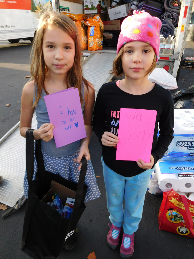 Jocelyn (left) and Genevieve (right) Sandrin, 8-year-old twins from Camas, bring cards with handwritten messages to the Lutz Hardware parking lot in downtown Camas, Friday, Nov. 16.