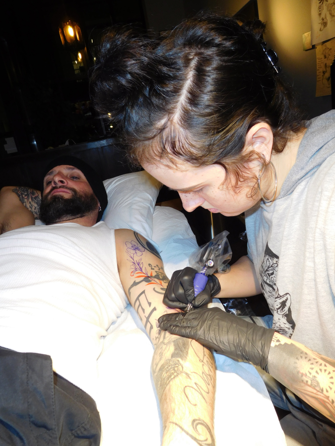 Eryn Rowe tattoos violets on Joshua Frost&#039;s arm, at 3rd Heart Tattoo.