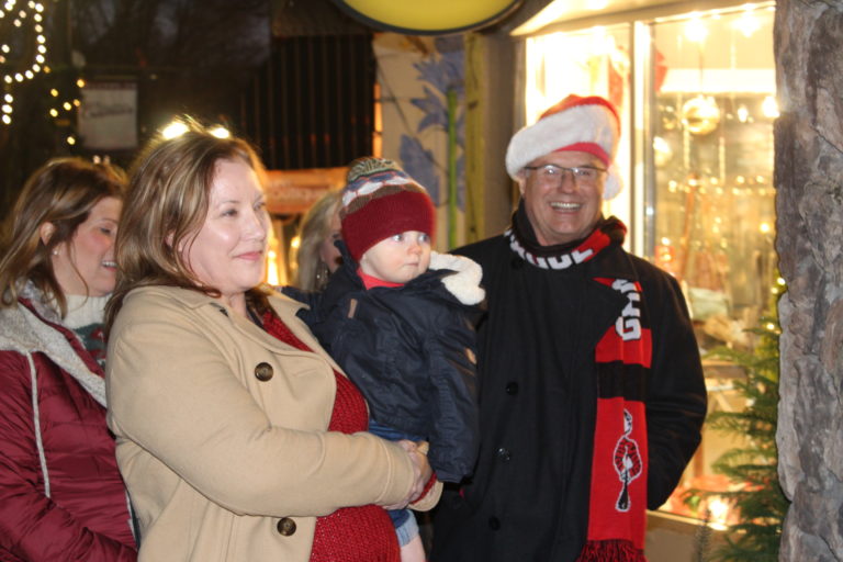 Newly appointed Camas Mayor Shannon Turk holds her grandson as she watches a ribbon cutting for Camas artist Heidi Jo Curley's new art studio in downtown Camas during the Hometown Holidays celebration on Friday, Dec. 7. 