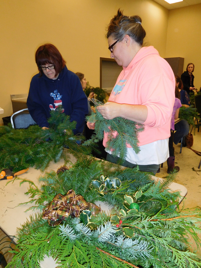 Patsy Dobbek, of Portland (left), and Tina Stauss, of Washougal (right) -- friends since the 1990s -- participate in a holiday wreath making workshop Dec. 1, in the Washougal Community Center. The Friends of the Washougal Library provided the wreath frames, greenery and ribbons.