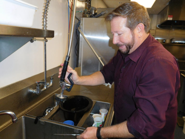 Robert Barber, chair of ReFuel Washougal and lead pastor of St. Matthew&#039;s Lutheran Church in Washougal, washes dishes at the Washougal-Camas severe weather shelter, Dec. 5, in the Washougal Community Center.