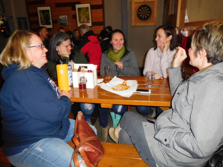 Sarah Howe (right, in background), a fan of music and sports trivia questions, enjoys socializing and laughing during her first ever trivia night with several friends, in their mid 30s to early 40s, on &quot;Team Redundancy Team,&quot; Dec. 5, at 54?40&#039; Brewing Company, in Washougal.