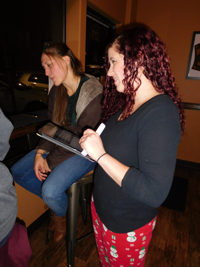 Laura Spain (right), host of the weekly trivia night at Mill City Brew Werks, in downtown Camas, walks around and checks each team&#039;s answer Dec. 5.