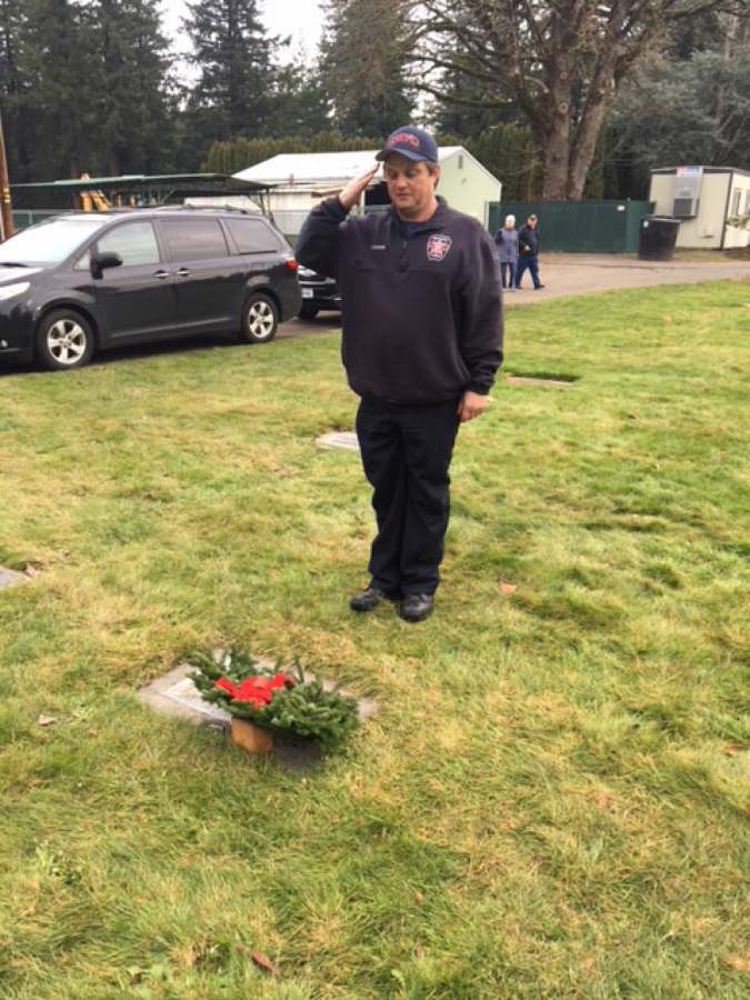 Butch Steigmann, a Camas-Washougal firefighter and Navy veteran, salutes a veteran after placing a wreath on a gravestone in the Camas Cemetery, following a &quot;Wreaths Across America&quot; ceremony.