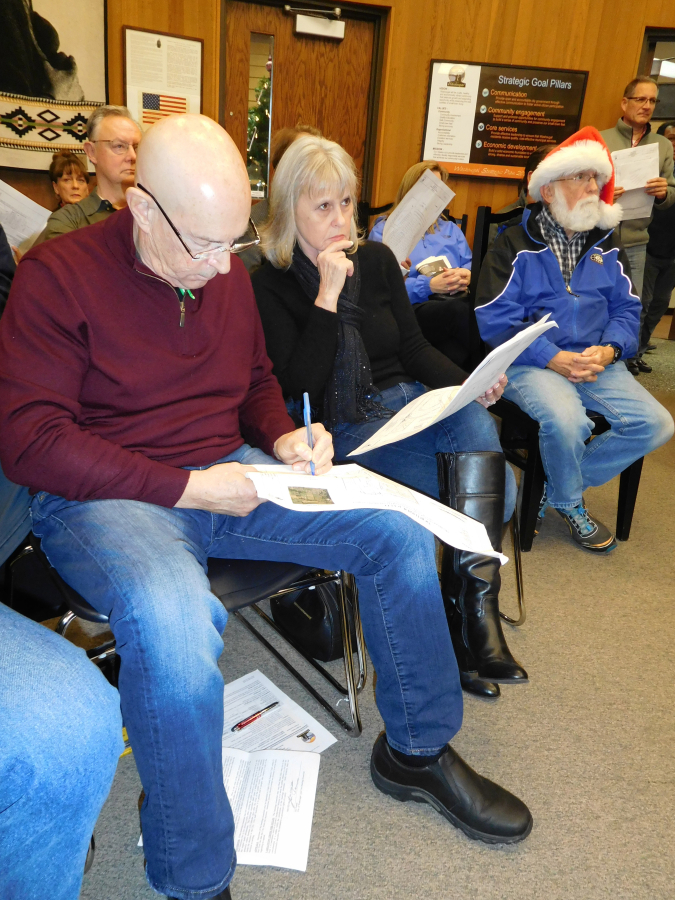 Larry Landgraver (left) and Judie Landgraver (center) take notes and listen during a Dec. 20 public hearing regarding a proposed residential development north of the Lookout Ridge neighborhood, in Washougal.