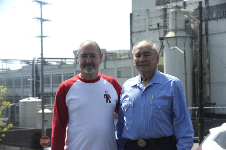 Kraig Nichols (left) and his father, Jerry Nichols (right), stand in the employee parking lot overlooking the Georgia-Pacific paper mill in downtown Camas in April 2018. Both men were part of the original start-up crew on the mill&#039;s No. 20 paper machine in 1984.