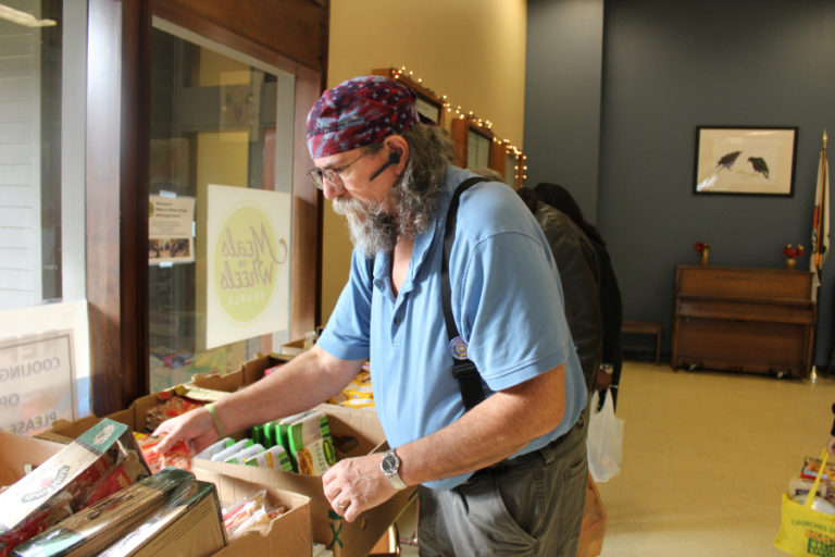 Charlie Walker, a regular volunteer at the Washougal Senior Center for the past 15 years, helps organize food in the center&#039;s weekly food bank line, on Monday, Jan.