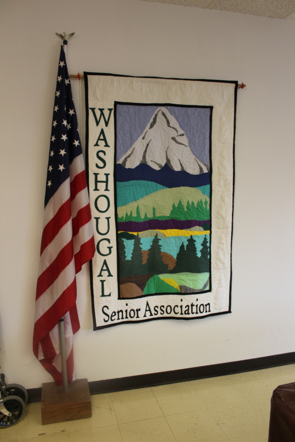A quilt displaying the Washougal Senior Association&#039;s logo, made by a former association member, hangs next to the United States flag in the &quot;back room&quot; of the Washougal Senior Center in downtown Washougal.