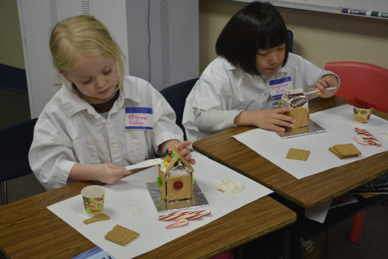 At left, Kaelyn Smith (left) and Ella Shimata (right) work on &quot;gingerbread&quot; houses using graham crackers and candy on Dec.