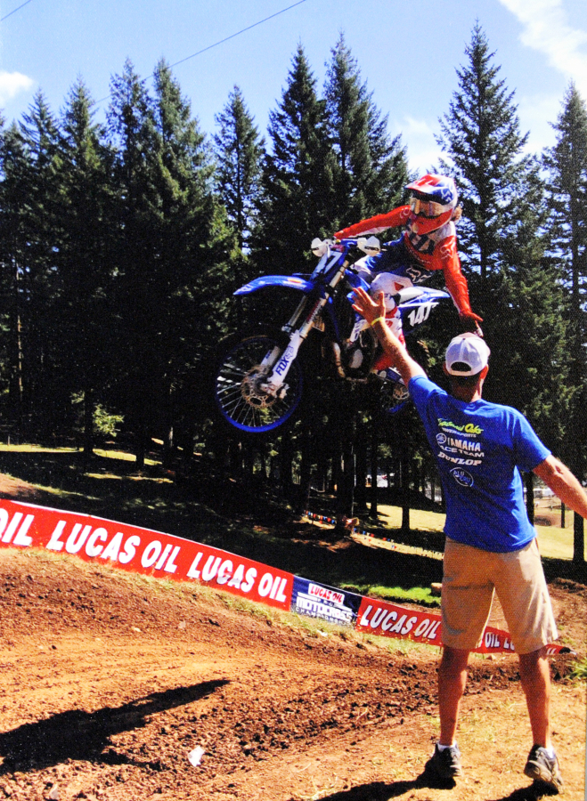Levi Kitchen gives his dad, Paul Kitchen, a high five while flying through the air at the Washougal Motocross Park.