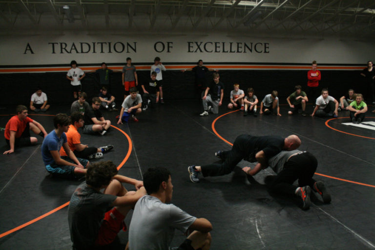 Assistant Washougal wrestling coach Rob Anderson (center, in black shirt) teaches a few wrestling moves during a recent practice.