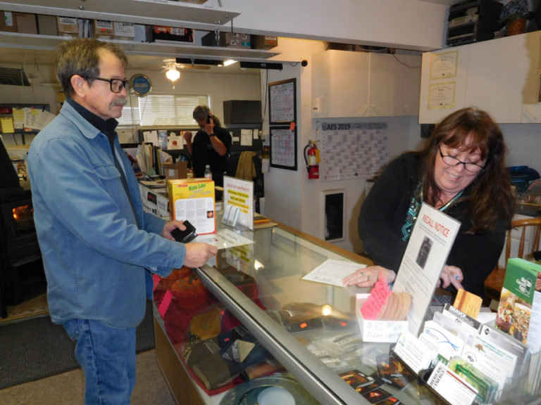 Dan Dilley answers a client&#039;s questions on the phone, while Marsha Dilley helps a customer at their business, &quot;A&quot; Your Town Chimney, in Washougal.