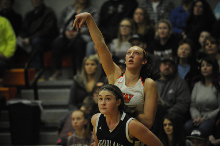 Washougal senior forward Beyonce Bea (back) keeps a sharp focus on her shot despite a physical blockout move by a Woodland player (front).