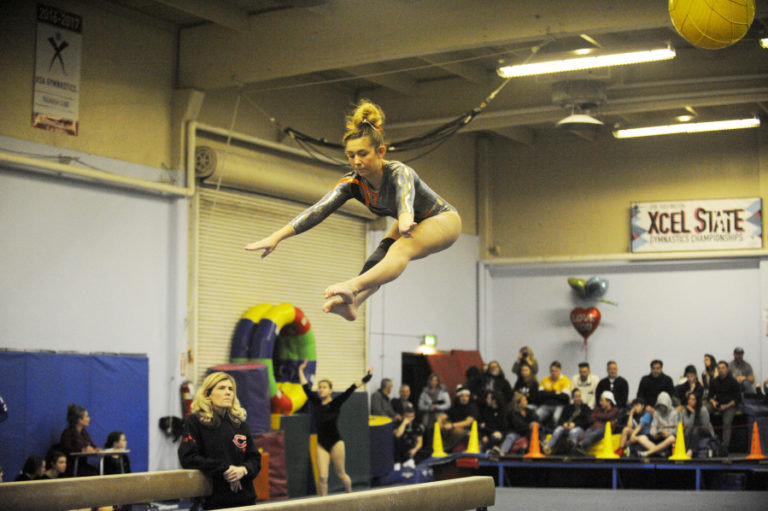 Washougal gymnast Katie Stevens performs on the beam under the watchful eye of coach Carol Willson. Stevens is one of two Washougal gymnasts who train with the Camas team.