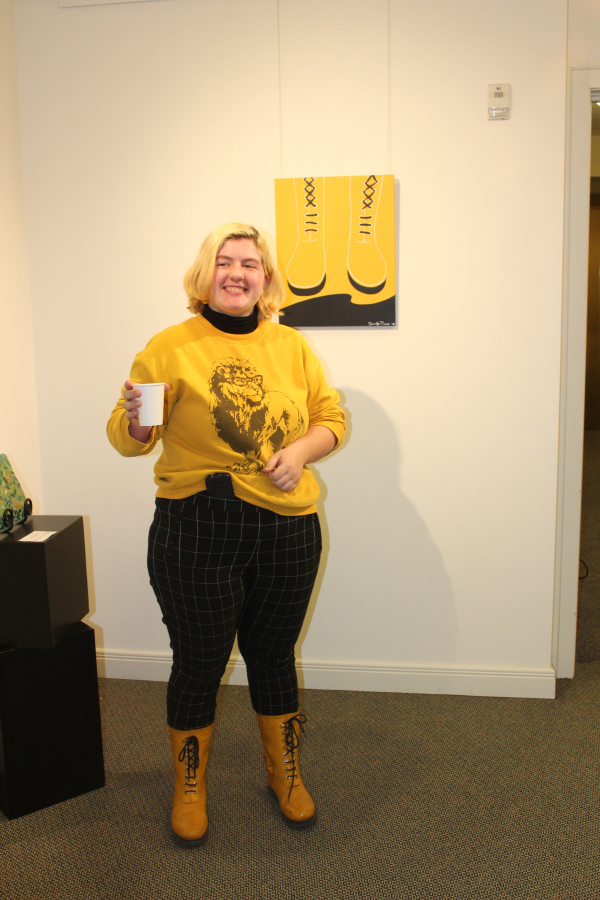 Alex Neal, 19, a 2018 Camas High grad, shows off her bright, yellow rain boots, which inspired the &quot;Yellow Boots&quot; painting by her mother, Jennifer Neal, shown here at Second Story Gallery.