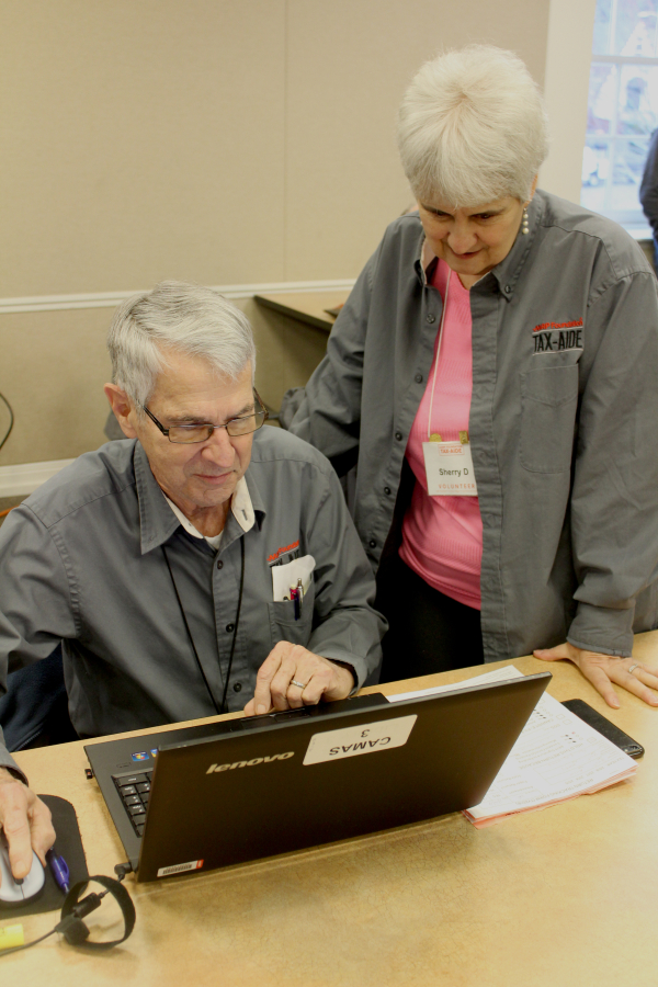 Local AARP Foundation Tax-Aide coordinator Sherry Davis (right) looks at a tax return prepared by Tax-Aide counselor Drew Snyder on Feb. 14, at the Camas Public Library.