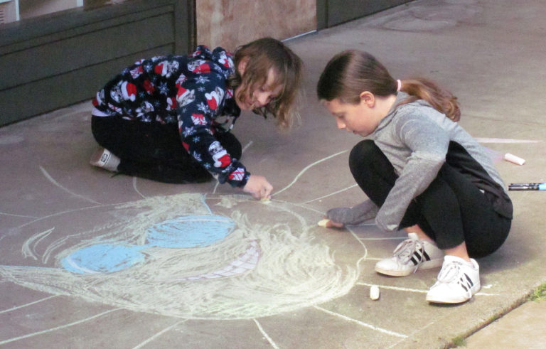 Hadley McCuen (left) and Cheyenne Jackson draw on the sidewalk next to Washougal Community Library during a chalk art event held as part of Washougal Youth Arts Month on March 9.