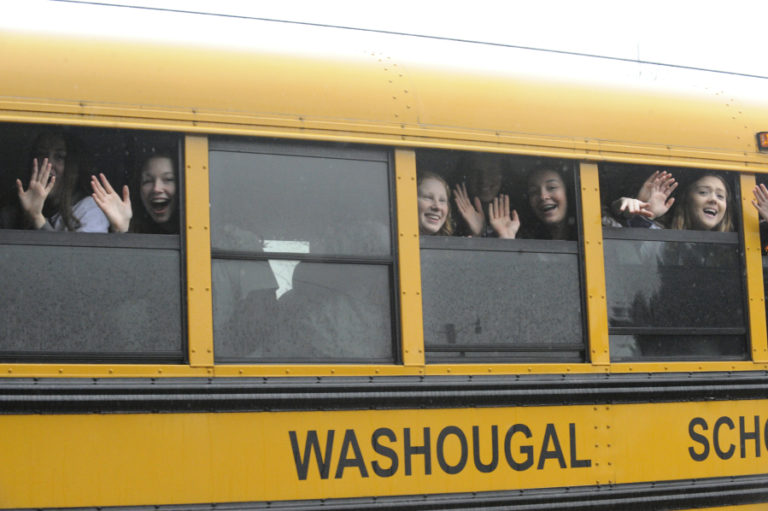 Members of the Washougal girls basketball team wave to fans from a school bus, led by police and fire department escorts on Friday, March 8.