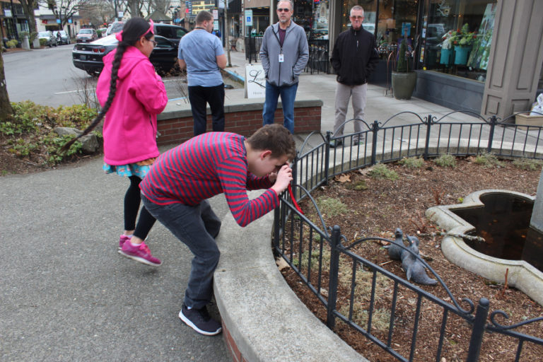 Fenix Roark, 15, an eighth-grader at the School for the Blind in Vancouver (front) takes a photo of a bird sculpture in downtown Camas on March 11, while his classmates, Inara McNew, 13 (left), and Nolan Schaffer, 17 (second from left) and their volunteer adult companions explore the corner for more photo opportunities.