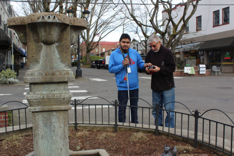 Student Husai Sanchez, 17, (left) and volunteer John Bannan (right) line up a camera to take a photo of the fountain near the Camas Hotel on Monday, March 11.