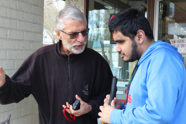 John Bannan, a volunteer at the Washington State School for the Blind (left), talks about photo opportunities with 17-year-old student Husai Sanchez (right) outside Lutz Hardware in downtown Camas on March 11.