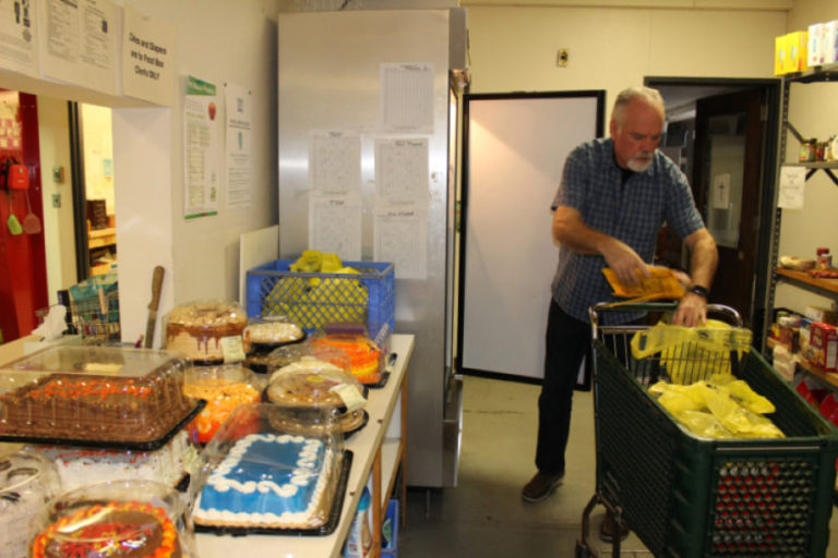 John McHugh, of Camas, loads frozen meats and donated baked goods from local grocery stores into food bags for families in need at the Inter-Faith Treasure House in November 2017. McHugh is one of 150 volunteers who keep Treasure House running.