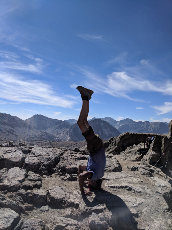 69 year old Dave Deal pops off this headstand at the top of Mather Pass in the high Sierras.