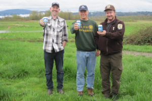 From left to right, Bolt Minister, Dave Pinkernell and Christopher Lapp stand near the Steigerwald National Wildlife Rufuge with cans of 54-40 Brewing Company's Restoration Ale. 