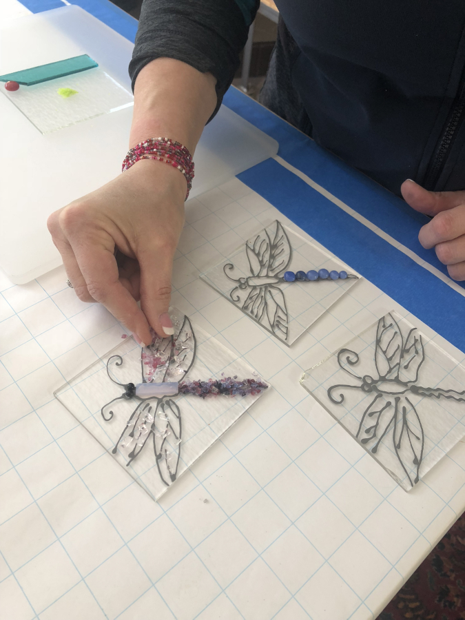 Washougal fused-glass artist Shirley Bishop demonstrates a method she teaches students that relies on using various pieces of glass, including the finely crushed &quot;grit&quot; she is placing on the dragonfly wings in this photos, to create a picture for a glass tile, coaster, slumped glass bowl or garden stake. Bishop will take part in the second annual Washougal Studio Artists Tour over Mother&#039;s Day Weekend, from 10 a.m. to 5 p.m., Saturday and Sunday, May 11-12.