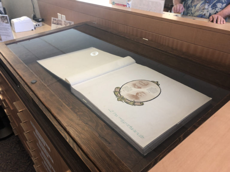 One of the three scrapbooks filled with Camas-Washougal history sits inside a wood and glass case at the Camas library.