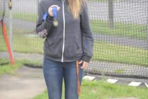 State champion discus thrower Kiersten De La Rocha holds her gold medal inside the throwing area at Washougal High School where she learned her craft. (Wayne Havrelly/Post-Record)