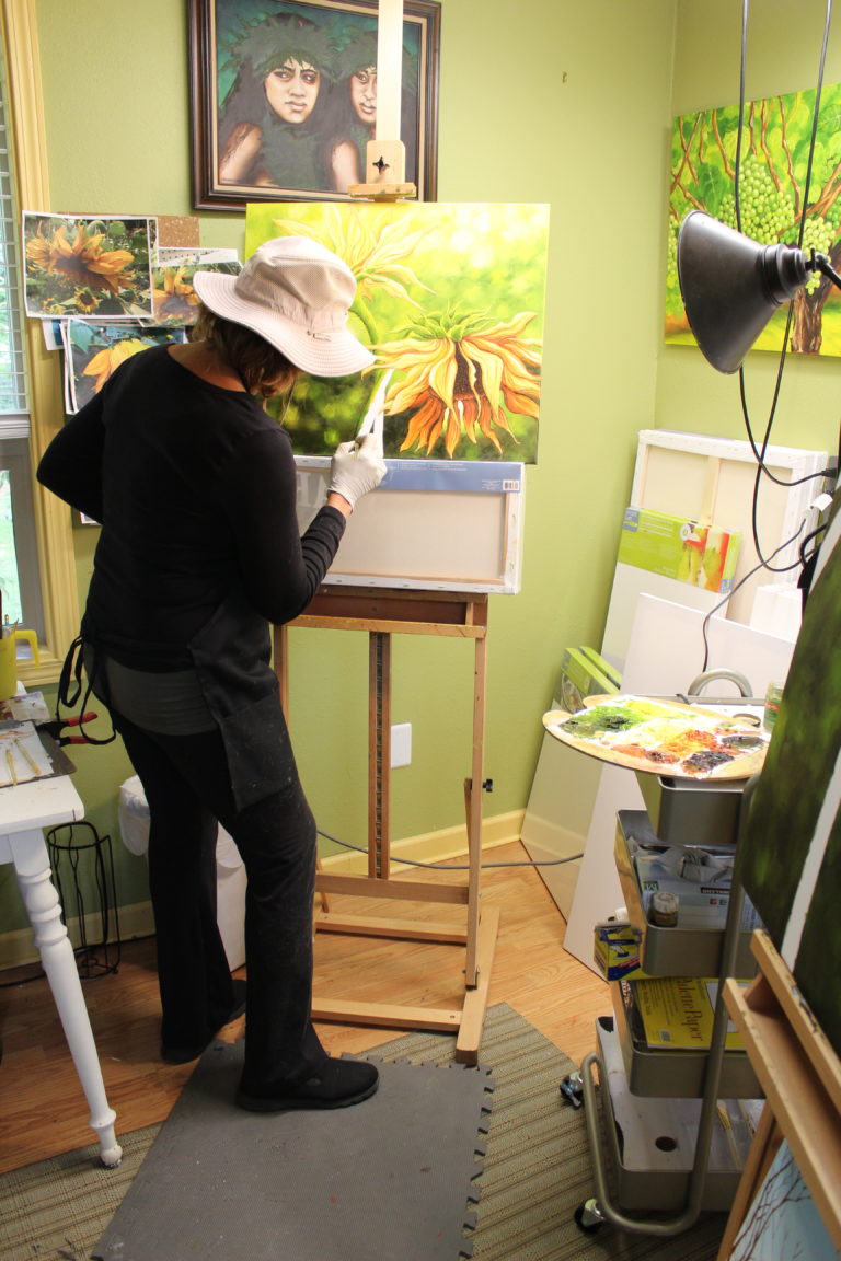 Former legislator turned artist-farmer Liz Pike finishes an oil painting of a sunflower inside the art studio at her Shangri-La Farm.