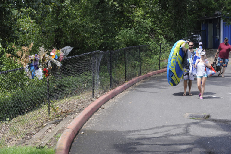 Visitors to the Sandy Swimming Hole pass a memorial on the fence at the Washougal park on July 12.