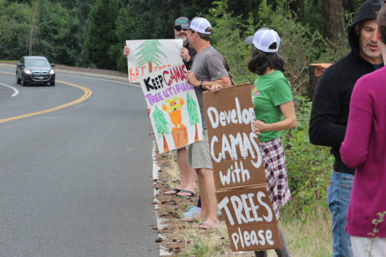 Geri Rubano (center), of Camas, holds a &quot;Develop Camas with trees please&quot; sign at a July 17 Camas Tree Protectors event near a new subdivision off Northwest 43rd Avenue in Camas.