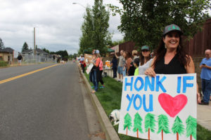 Heather Kesmodel, of Camas, holds a "Honk if you (love trees)" sign at a July 17 Camas Tree Protectors event on Northwest 43rd Avenue in Camas.
Below, Geri Rubano (in green), of Camas, holds a "Develop Camas with trees please" sign at a July 17 Camas Tree Protectors event. (Photos by Kelly Moyer/Post-Record)